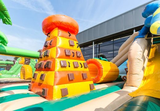 Colored inflatable park in jungle theme with slides, 3D objects, crawl tunnel and climbing tower for children. Buy bouncy castles online at JB Inflatables UK