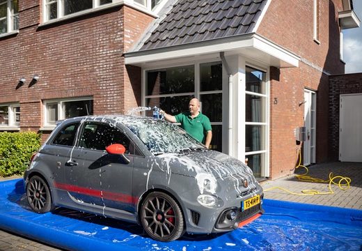 Man maakt auto schoon op mobiele wasplaats